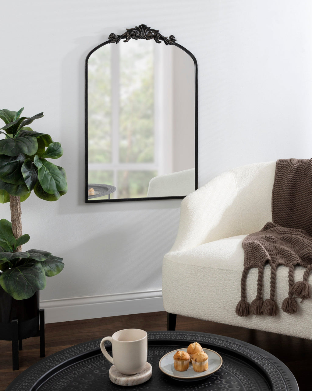 Living room with a white sofa, decorative mirror, and small table with a cup and snacks.