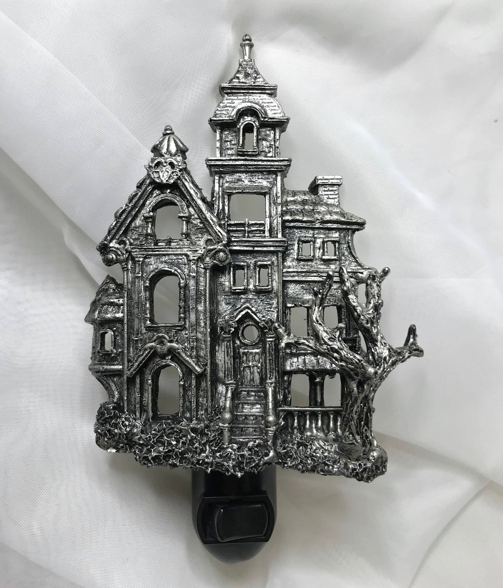 Metallic haunted house ornament on a white fabric background
