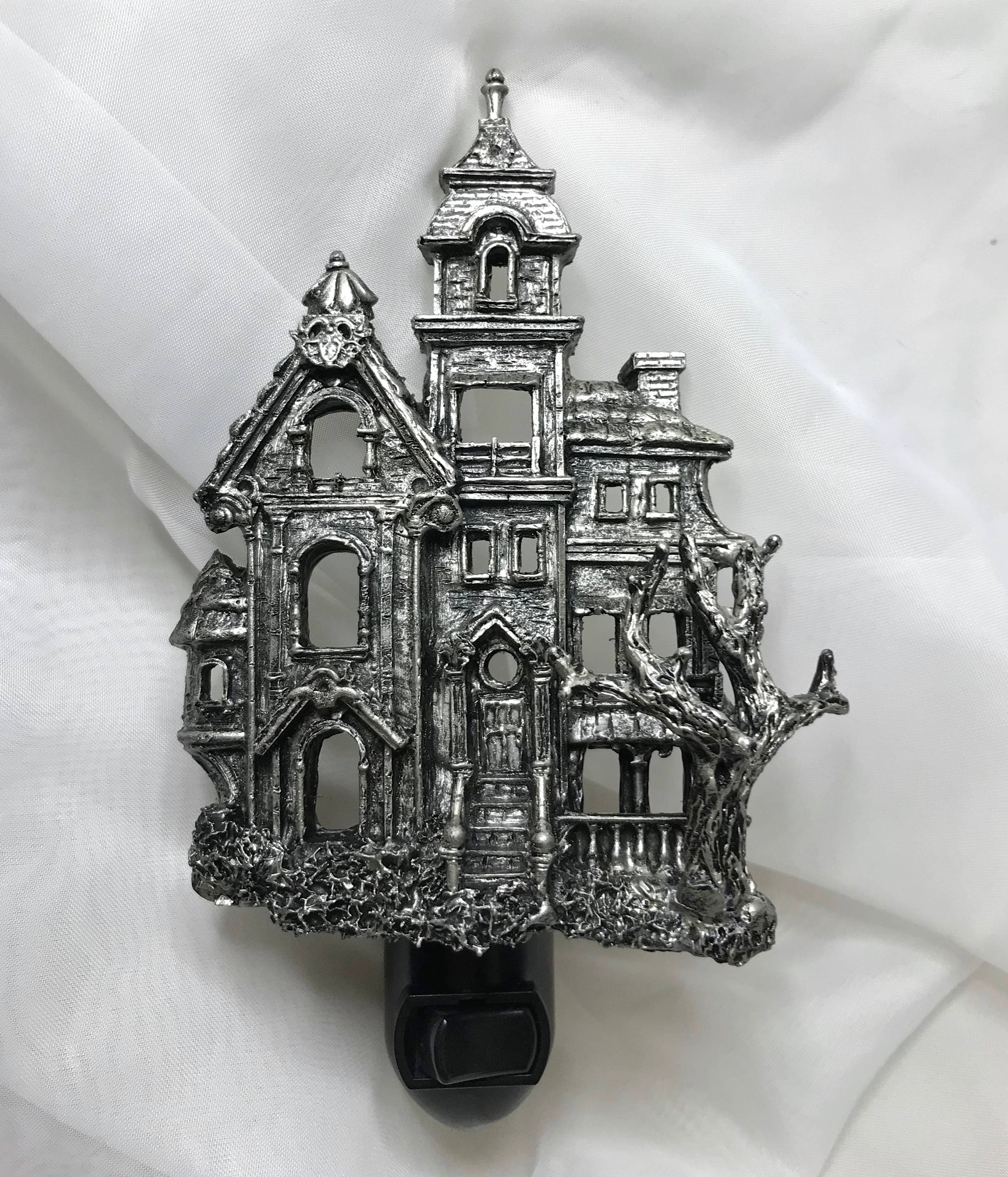 Metallic haunted house ornament on a white fabric background