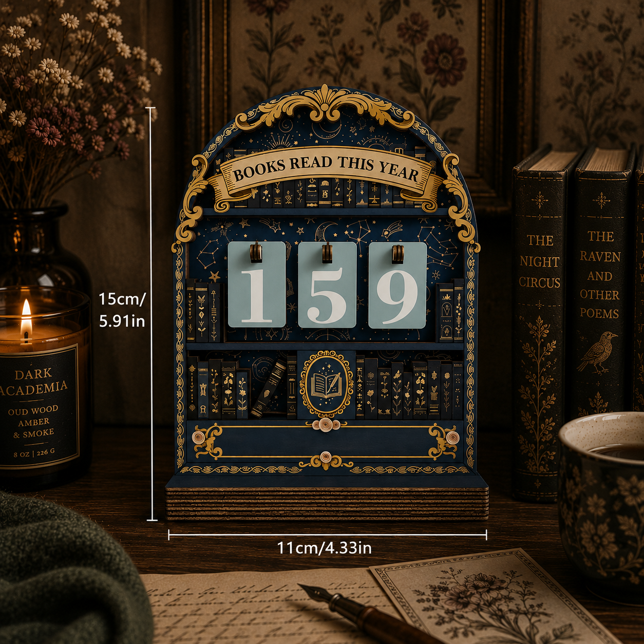 A decorative flip-year calendar styled like an antique book, shown on a wooden table with books, a candle, and a cup in a cozy room setting. White measurement lines indicate 15cm height and 11cm width.