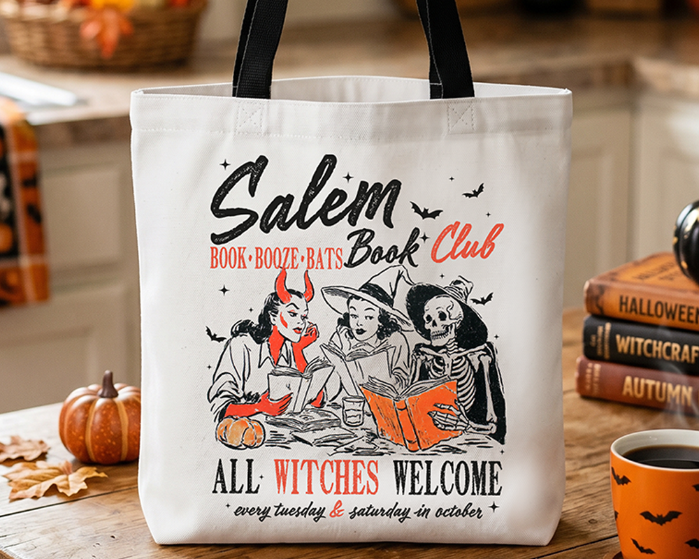 Tote bag with 'Salem Book Club' design on a table with pumpkins and books.