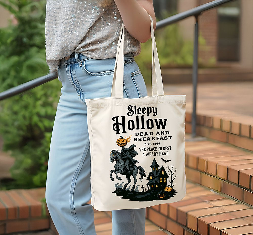 Person holding a tote bag with 'Sleepy Hollow' design outdoors.