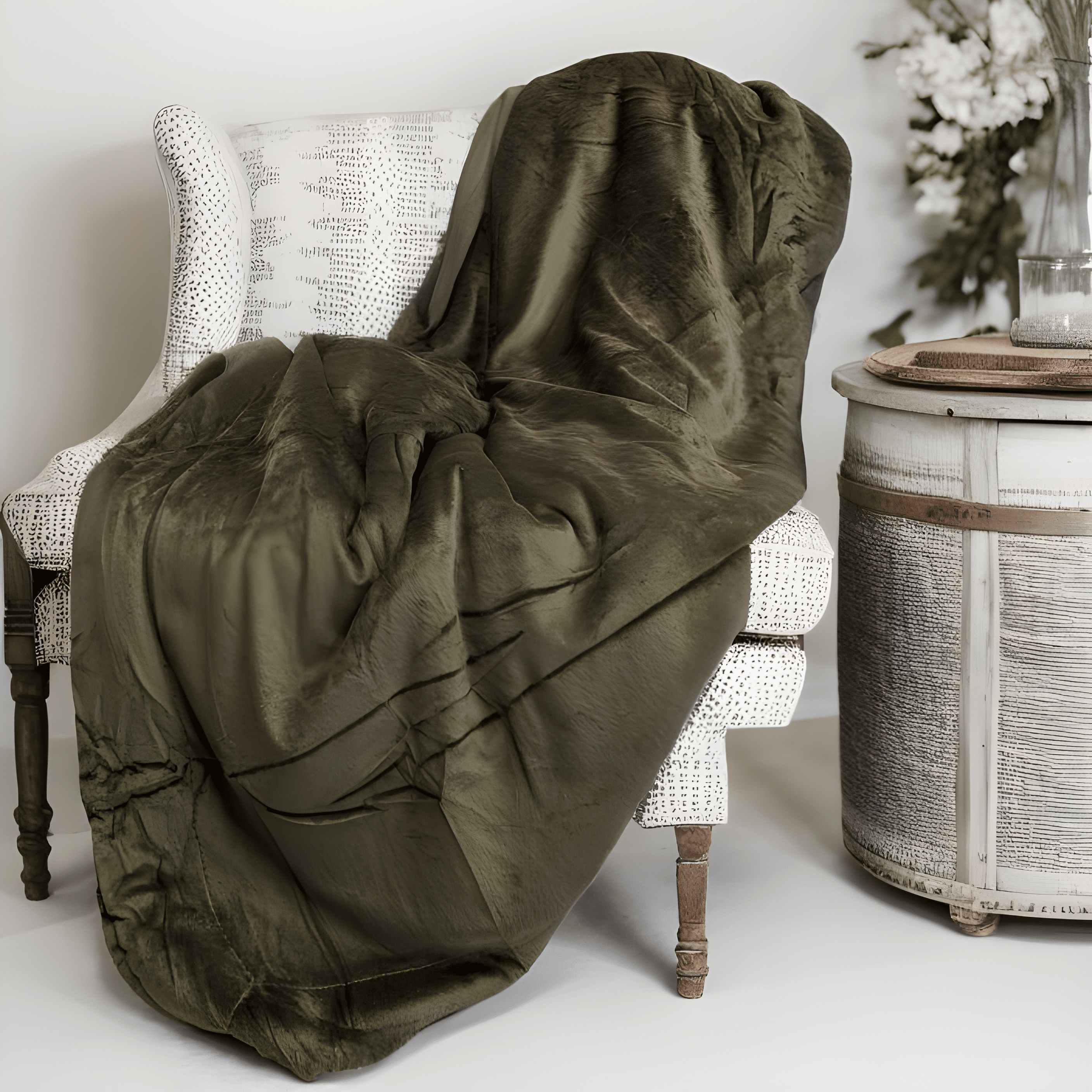 Green blanket draped over a chair in a room with a decorative side table.