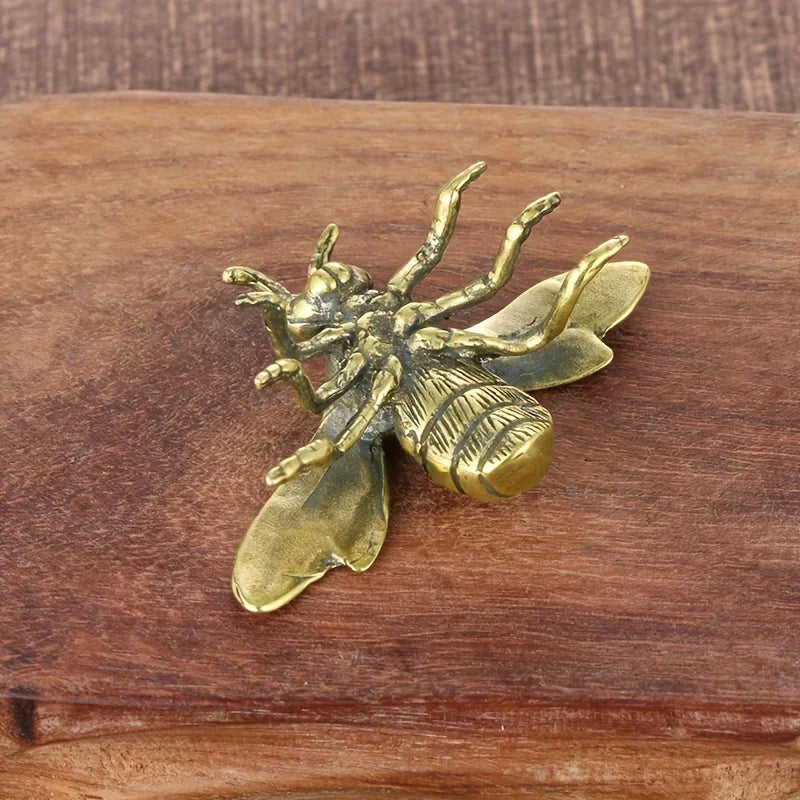 Bronze bee sculpture on a wooden surface