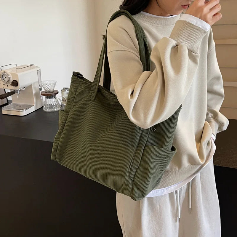 Person holding a green tote bag in a home setting