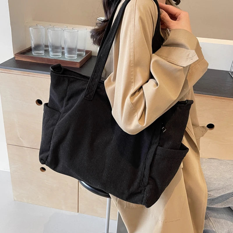 Person holding a black tote bag in an indoor setting