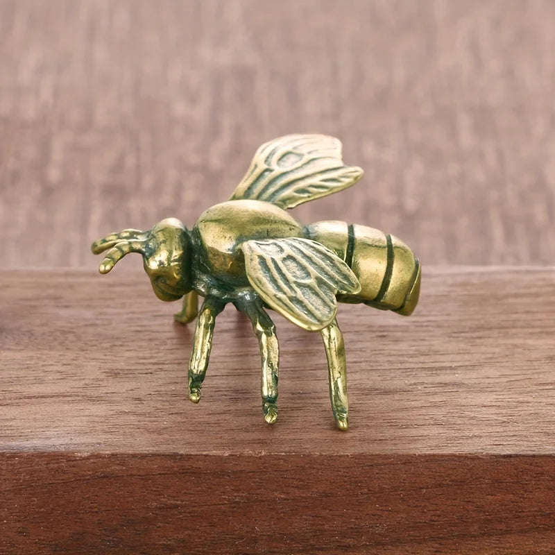 Bronze bee figurine on a wooden surface