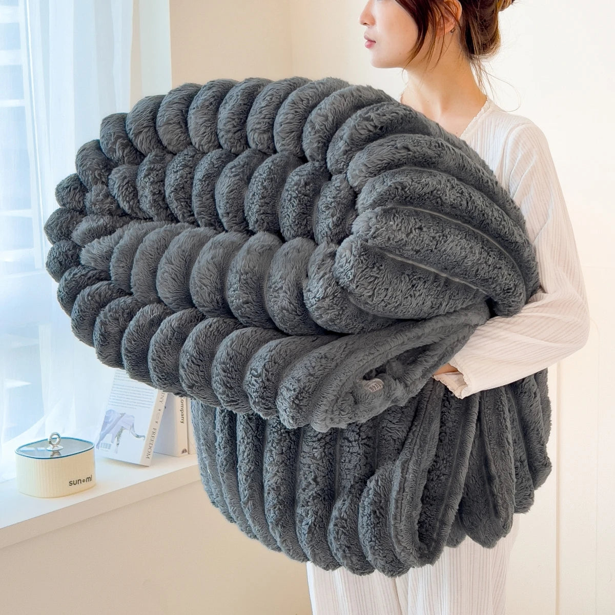 Person holding a large gray textured blanket indoors
