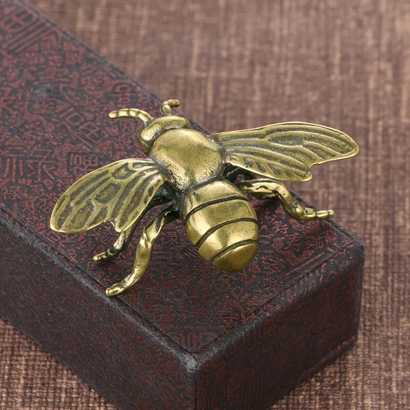 Bronze bee sculpture on a textured brown surface