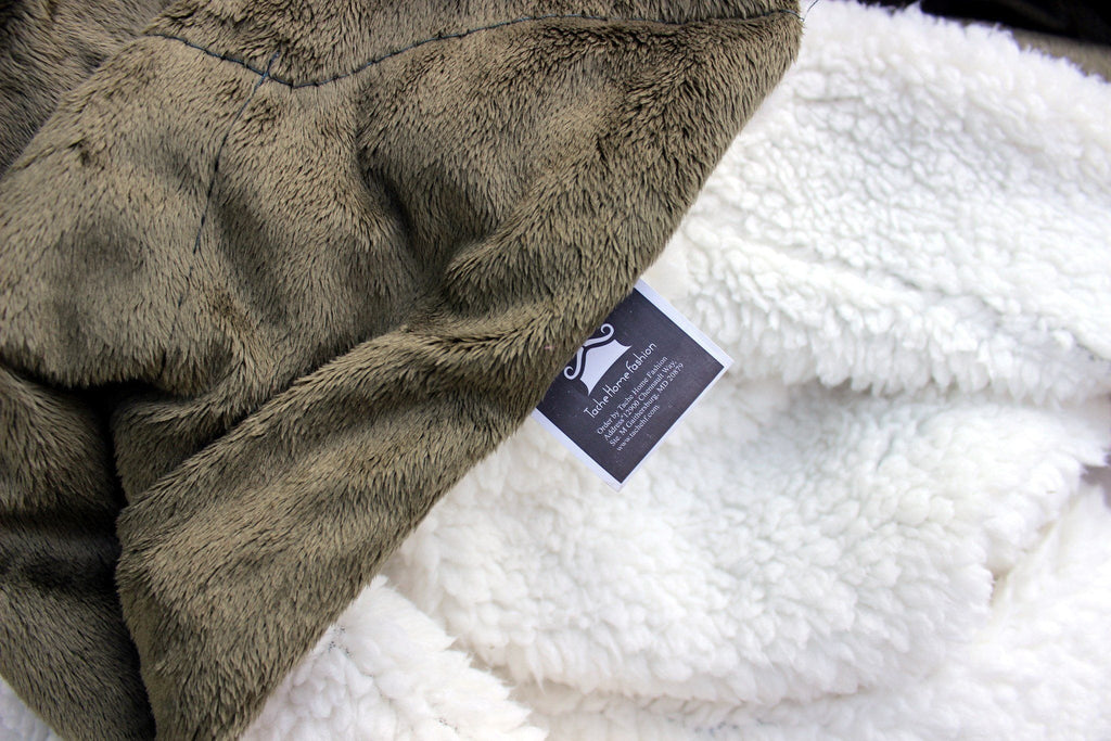 Close-up of a textured gray blanket with a brand tag on a white surface