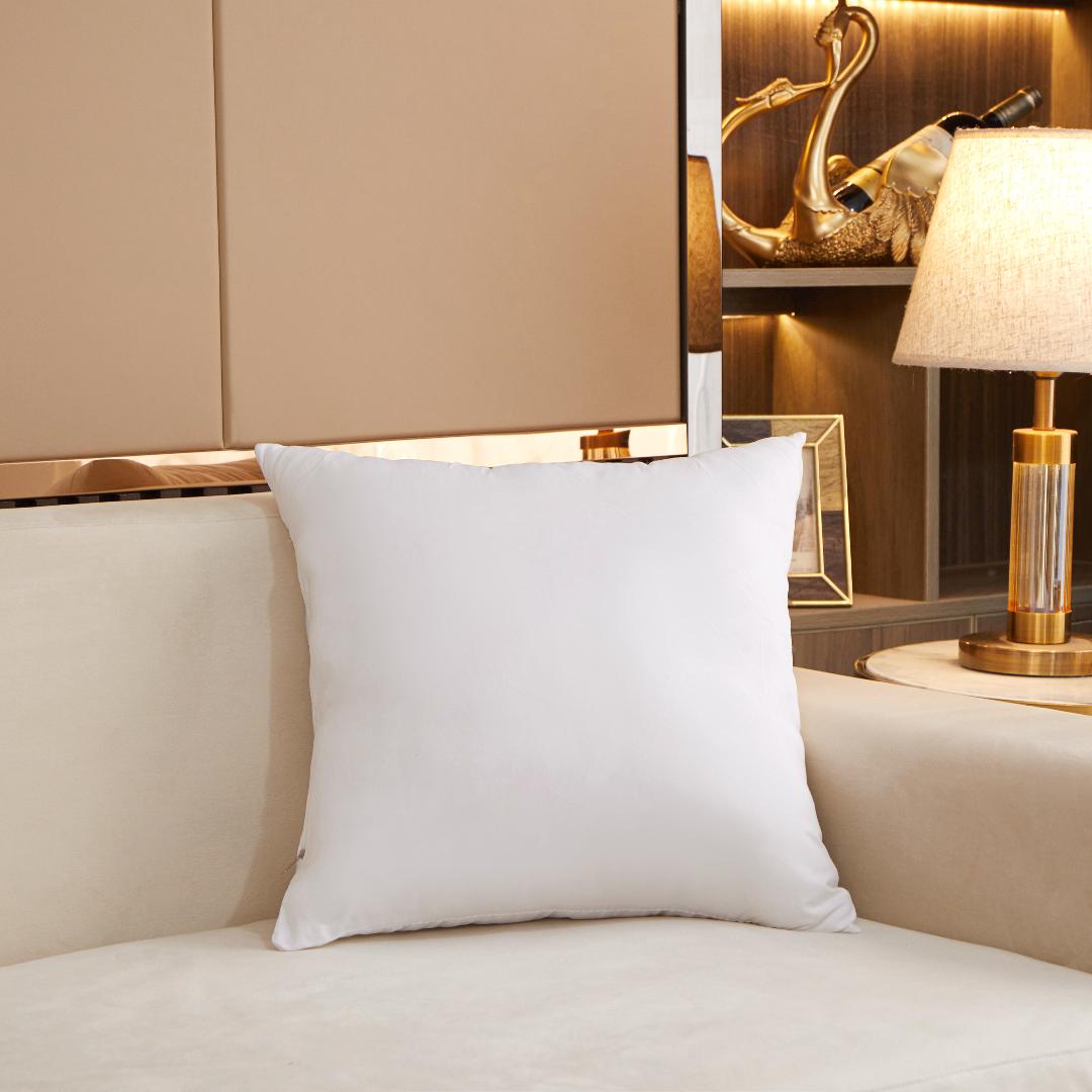 White pillow on a beige sofa with decorative elements in the background